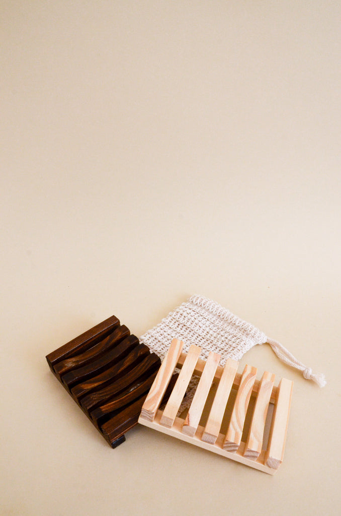 Two Lena Laced wooden soap dishes and one soap pouch. One dish is a dark espresso wood and the other is a natural cream wood, showing the two options. 